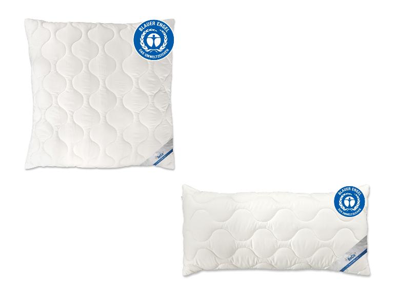 Deux oreillers blancs matelassés, un carré et un rectangulaire, avec des étiquettes environnementales bleues.