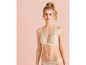 Une femme porte un soutien-gorge et une culotte beige en dentelle.