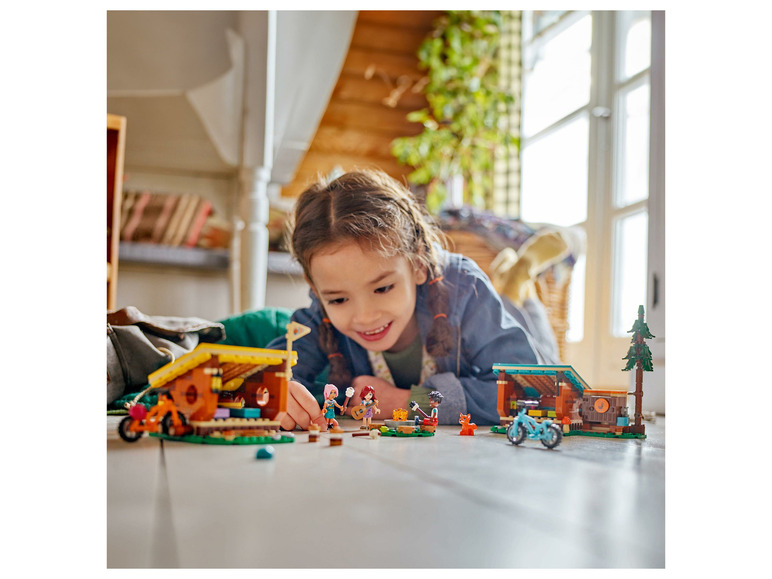 Une fille joue avec des ensembles LEGO Friends de cabanes en bois et de vélos.
