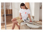 Une femme portant un t-shirt blanc avec un imprimé de palmiers lit un livre sur le canapé.