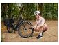 Femme gonflant le pneu d'un vélo électrique Crivit avec une pompe portable en forêt.