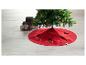 Jupe de sapin de Noël rouge avec lumières et cadeaux sur un sol clair.