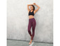 Femme en soutien-gorge de sport noir et leggings violets à motif géométrique.