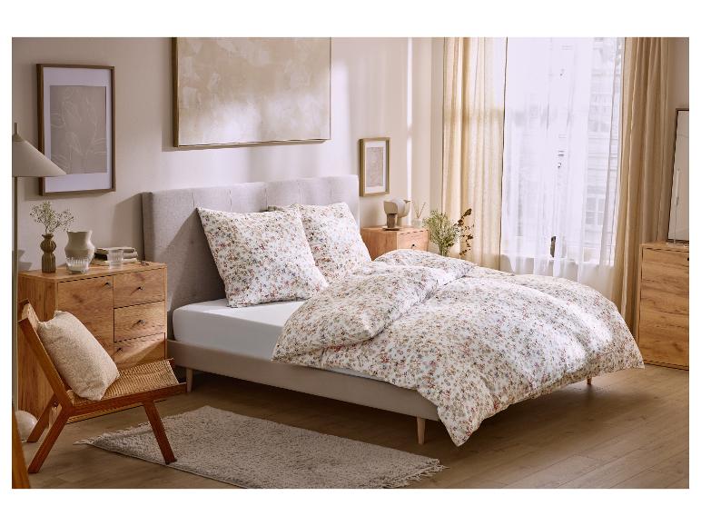 Chambre avec lit double, parure de lit fleurie, tables de chevet en bois et décoration.