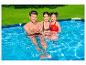 Famille heureuse dans une piscine hors sol, avec pelouse verte en arrière-plan.