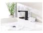 Robinet noir moderne, lavabo blanc et accessoires de salle de bain.