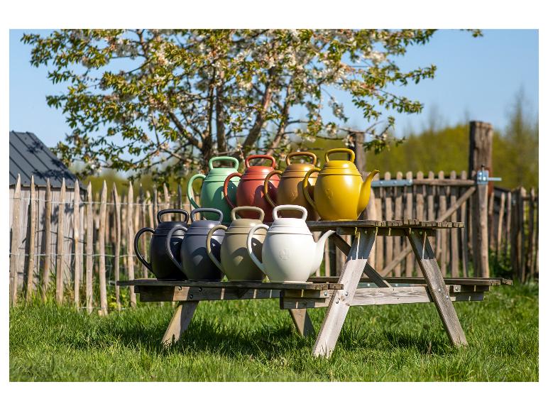 Arrosoirs colorés sur une table de pique-nique en bois dans un jardin.