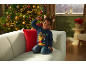 Enfant souriant en pull de Noël bleu et serre-tête de renne sur le canapé.