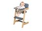 Bébé souriant assis dans une chaise haute en bois et grise.