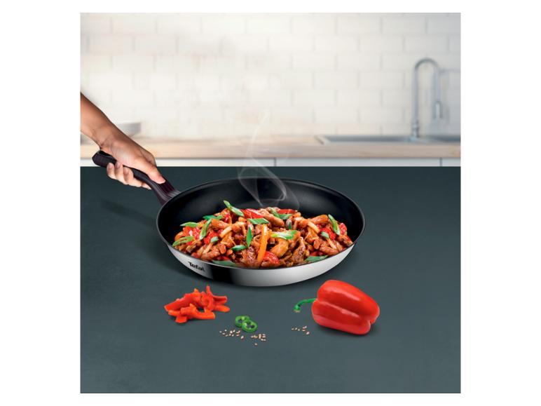 Poêle avec un sauté de viande et légumes, avec des poivrons à côté.
