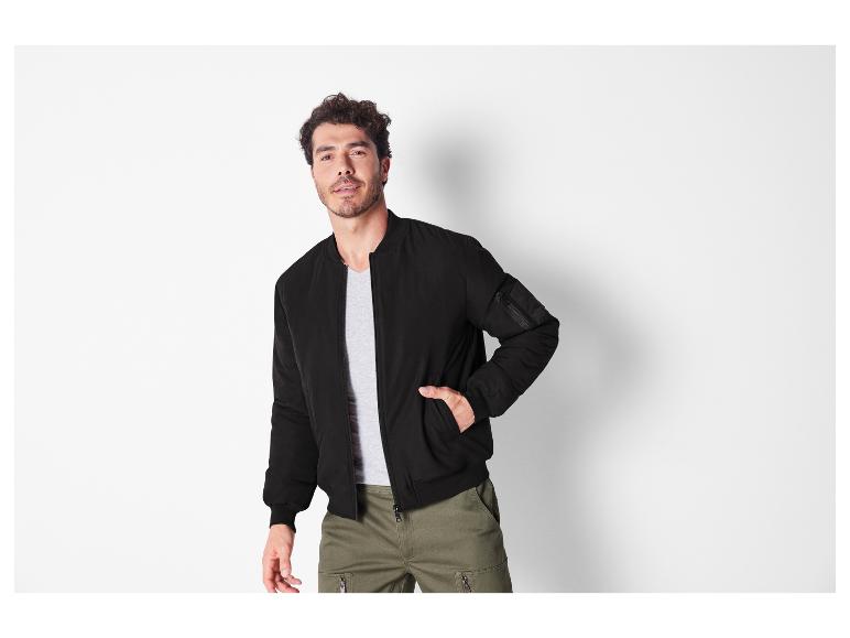Homme portant une veste bomber noire et un pantalon cargo vert.