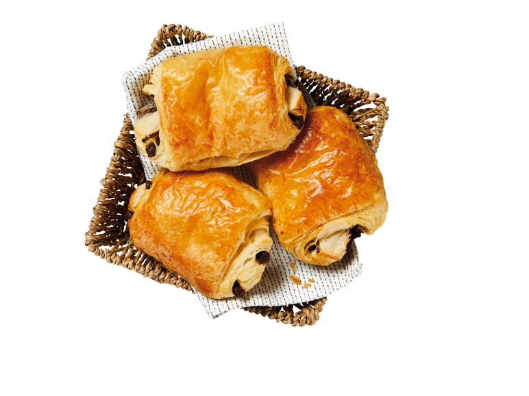 Trois pains au chocolat dorés dans un panier en osier.
