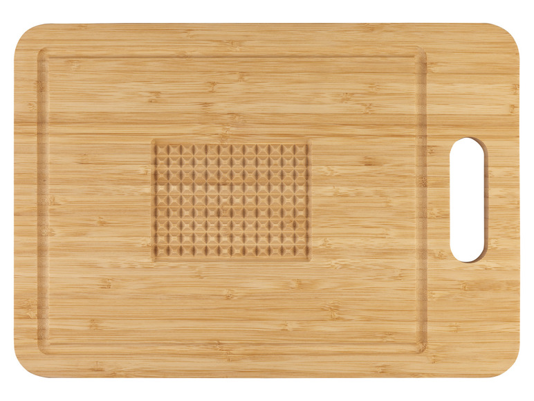 Une planche à découper en bois avec une poignée et une zone gravée.