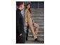 Une femme en costume beige et bottes noires est sur un escalier.