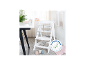 Chaise haute en bois blanc avec plateau et harnais de sécurité, à côté d'une table avec vaisselle pour bébé.