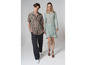 Un homme et une femme en tenue décontractée, il porte une chemise beige à imprimé et un pantalon noir, elle porte une robe bleu clair.