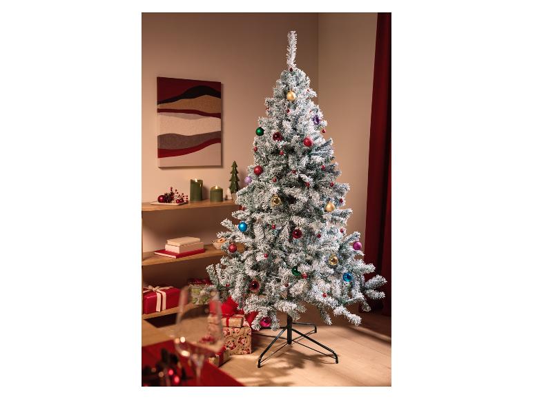 Un sapin de Noël floqué avec des ornements colorés dans un salon festif.