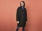 Une femme portant un manteau noir et un jean bleu.