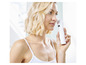 Une femme utilise un appareil de beauté sans fil blanc de Foreo sur son visage.
