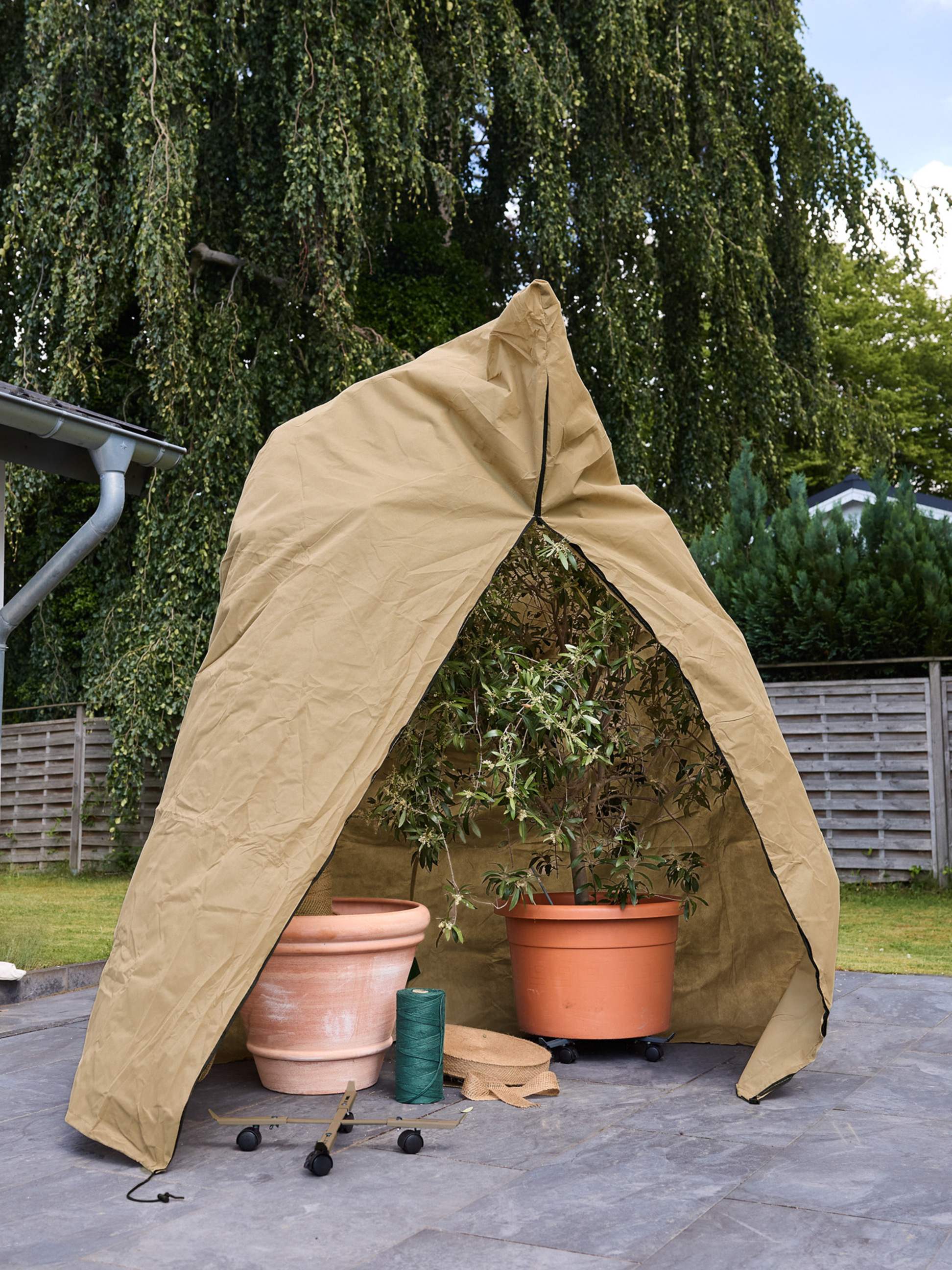 Housse de protection hivernale pour plantes en pot sur une terrasse.