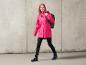 Une femme portant un imperméable rose et des bottes bleues avec un sac à dos.