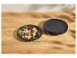 Assiettes noires avec une salade de fruits et légumes sur une table en bois.