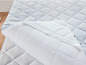 Un protège-matelas blanc avec un dessus bleu matelassé.