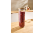 Bocal en verre avec couvercle en bois rempli de baies de goji séchées sur une table en bois.