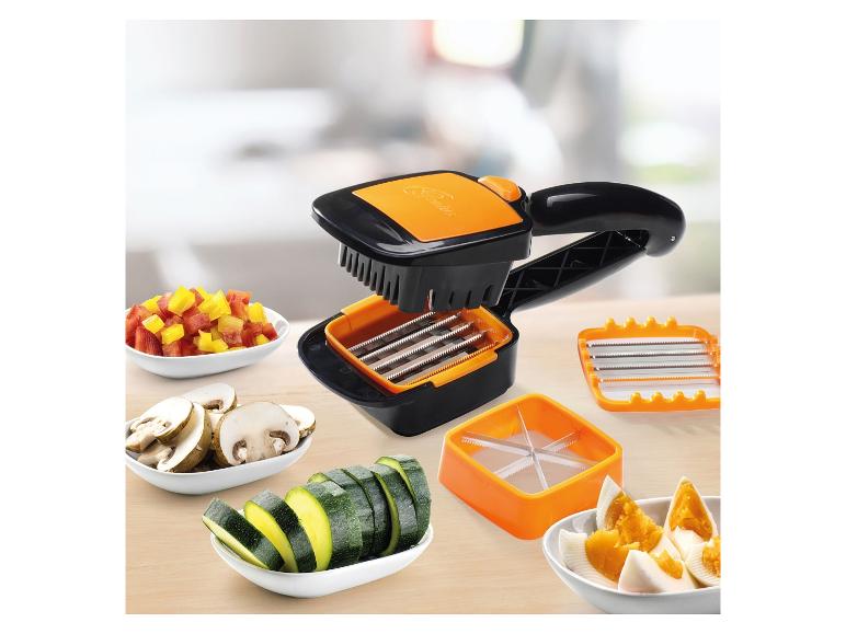 Coupe-légumes noir et orange avec accessoires et légumes coupés dans des bols.