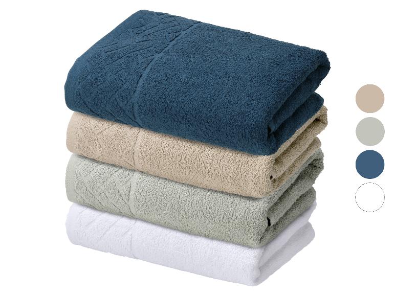 Pile de quatre serviettes de couleurs bleue, beige, verte et blanche.