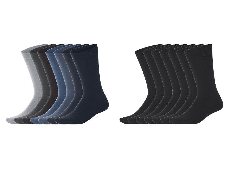 Deux paquets de chaussettes pour hommes : un avec des nuances de gris et de bleu, l'autre avec des chaussettes noires.