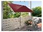 Un parasol rouge sur un balcon avec une chaise longue et des plantes.