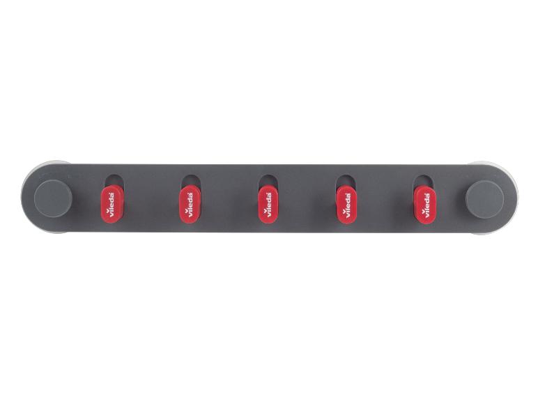 Support mural gris avec cinq pinces rouges pour les outils de nettoyage.