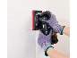 Mains gantées utilisant une ponceuse vibrante sans fil sur un mur.
