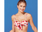 Une femme porte un bikini blanc avec un imprimé floral rouge.