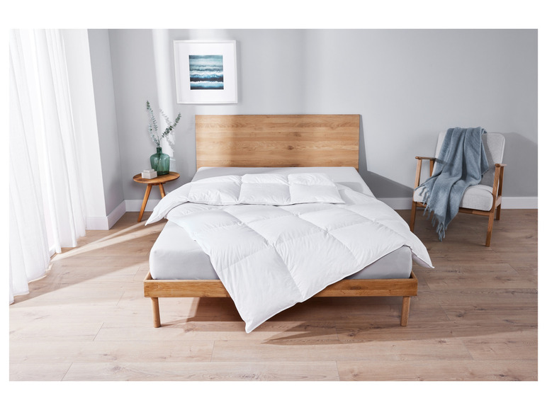 Une couette blanche sur un cadre de lit en bois dans une chambre à coucher.