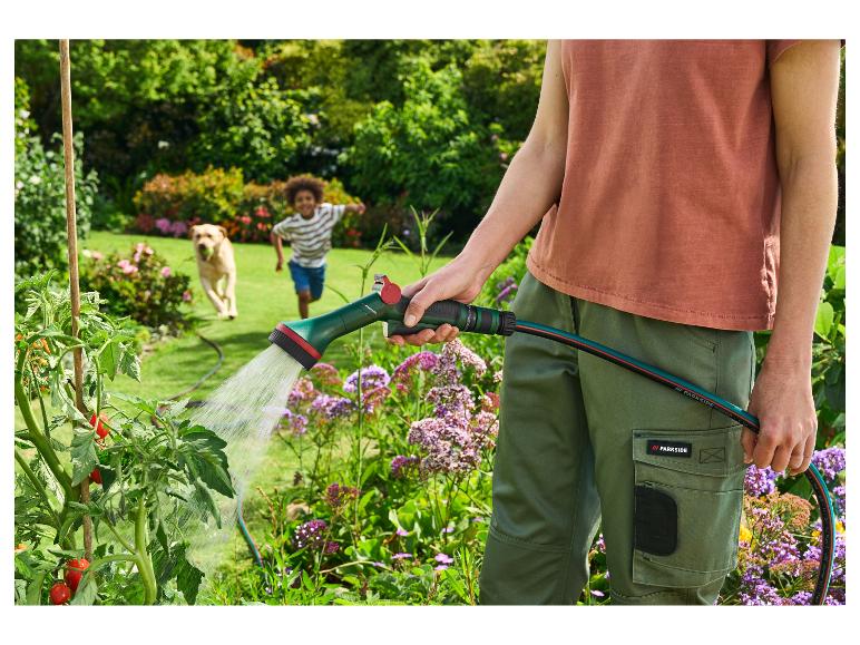 Personne arrosant des tomates avec un tuyau d'arrosage PARKSIDE, enfant et chien en arrière-plan.