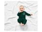 Un bébé porte une combinaison verte à motifs de dinosaures.
