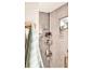 Panier de douche triangulaire avec du shampoing et du gel douche dans une salle de bain moderne.