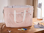 Un sac rose avec une machine à coudre, du fil, des boutons et des ciseaux.