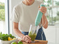 Une femme utilise un mixeur plongeant Rivercrest pour faire du pesto.