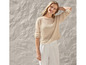 Femme portant un pull beige en maille et un pantalon blanc.