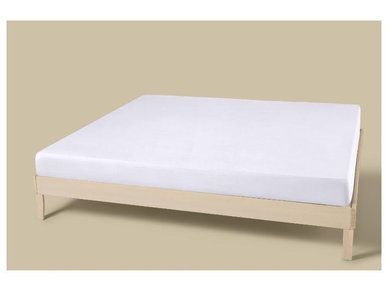 Matelas blanc sur un cadre de lit en bois.
