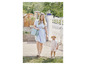 Une femme en robe bleue porte un sac vert et marche avec une petite fille en salopette.