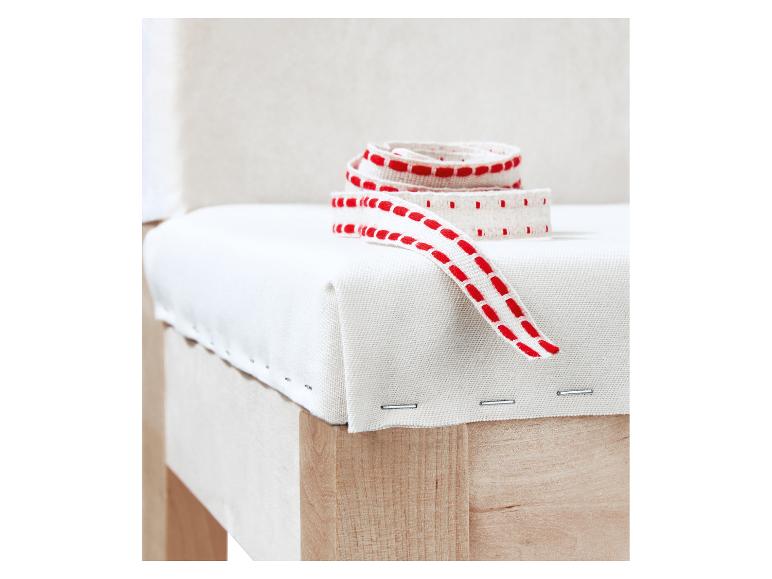 Chaise rembourrée blanche avec un ruban rouge et blanc à motifs dessus.