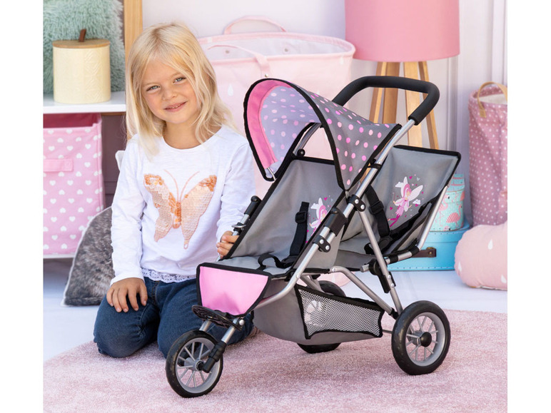 Une fille avec une poussette de poupée rose avec un motif papillon.