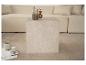 Table basse en marbre clair avec vase et livres sur un tapis beige.