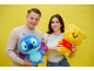 Deux jeunes tiennent des peluches, un alien bleu et un ours jaune, souriant à la caméra.