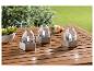 Trois bougeoirs LED argentés sur une table en bois.