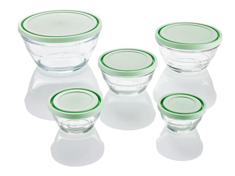 Quatre bols en verre avec des couvercles verts.